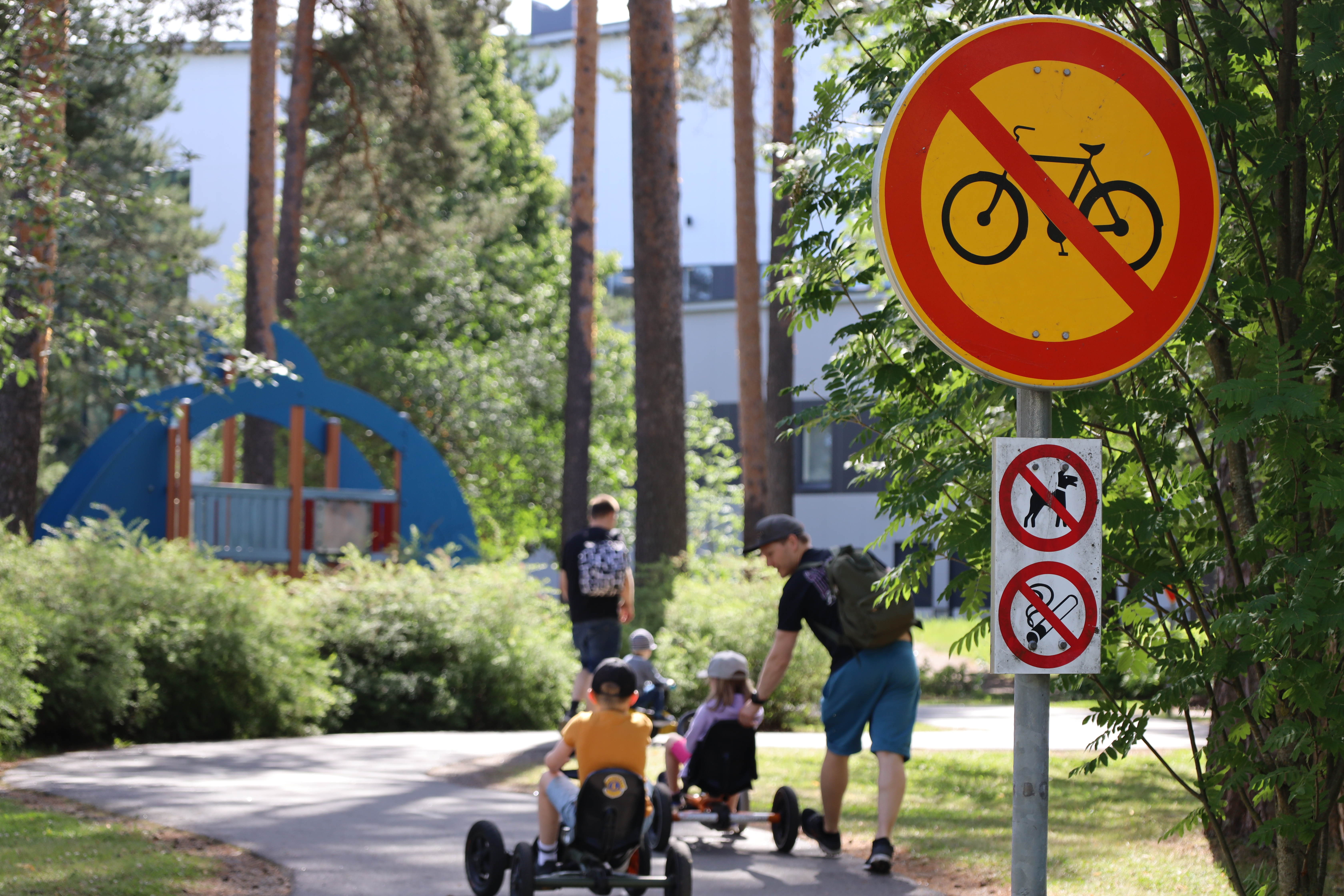 Lapsia ja aikuisia Lappeenrannan liikennekaupungissa, edustalla pyöräilyn kieltävä liikennemerkki.